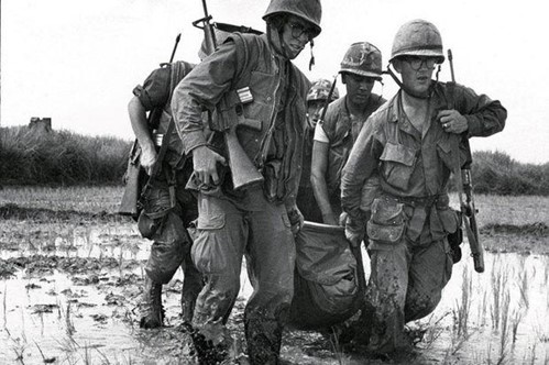 Foto van een groep Amerikaanse soldaten die een dode soldaat dragen naar veiligheid door moder en moeras